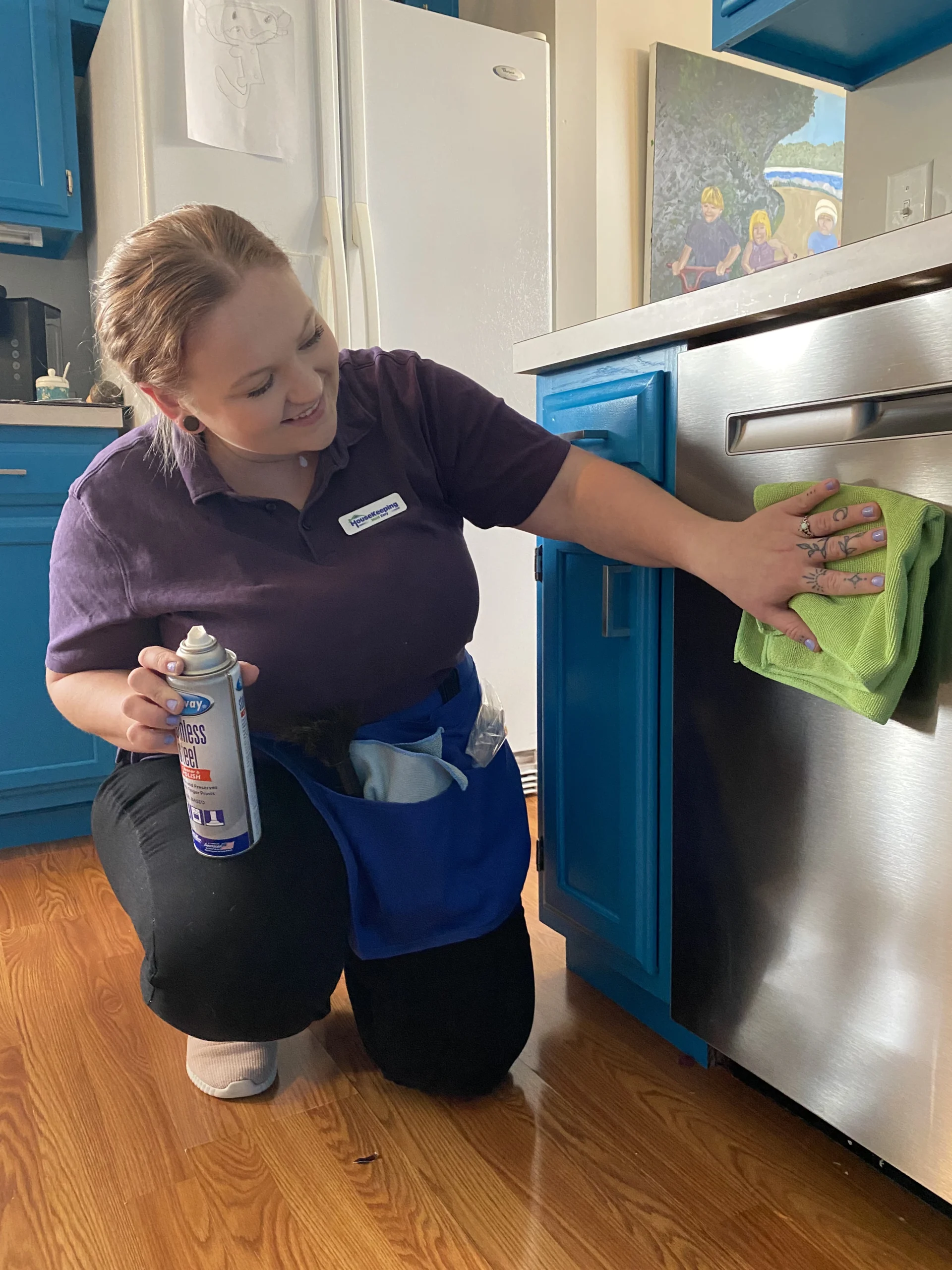 Professional cleaner polishing stainless steel oven during move-out cleaning service in modern kitchen.